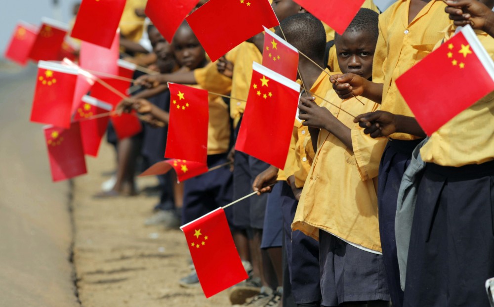 Liberian children hold Chinese flags before the arrival of China's President Hu in Monrovia
